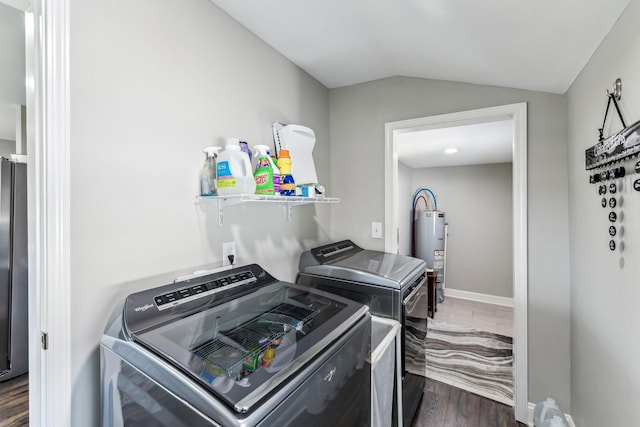 clothes washing area featuring dark wood-style flooring, baseboards, laundry area, water heater, and washer and clothes dryer
