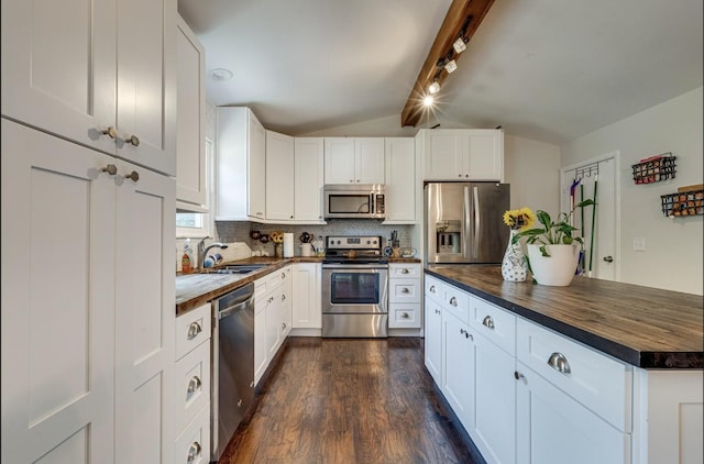 kitchen featuring a sink, vaulted ceiling with beams, appliances with stainless steel finishes, and wood counters