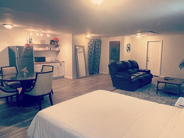 bedroom featuring dark wood-style floors, freestanding refrigerator, and baseboards