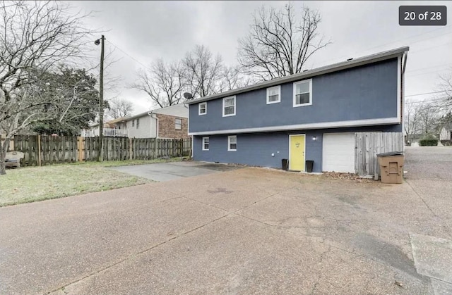 back of house featuring concrete driveway and fence