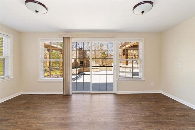 unfurnished room with dark wood-type flooring, plenty of natural light, and baseboards