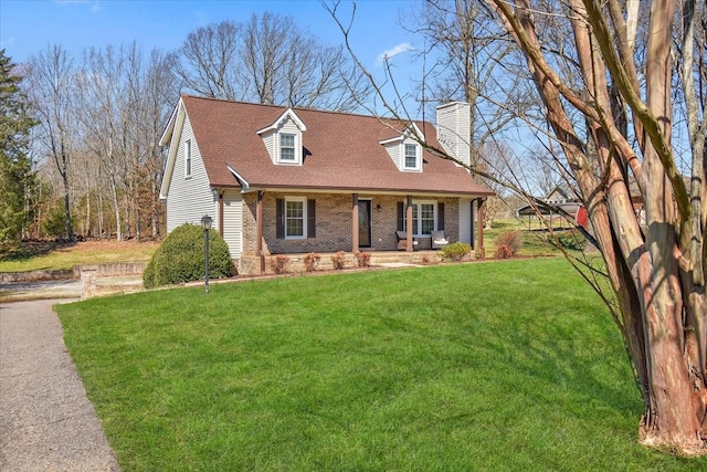 cape cod-style house featuring brick siding, a chimney, a front lawn, and roof with shingles