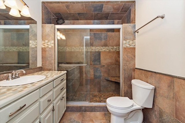 full bathroom with a stall shower, toilet, tile walls, and vanity