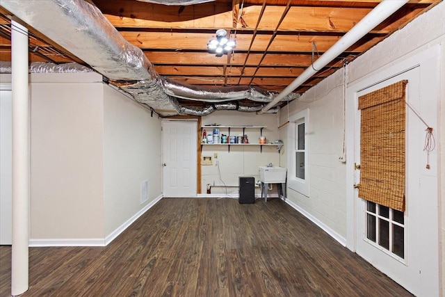 unfinished below grade area featuring visible vents, a sink, baseboards, and wood finished floors