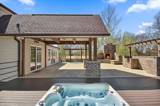 wooden deck with a lit fireplace and hot tub deck surround