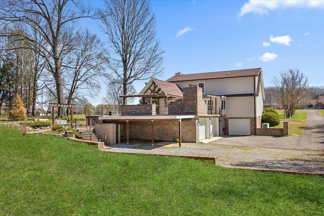 back of property featuring stairway, a wooden deck, gravel driveway, a garage, and a lawn