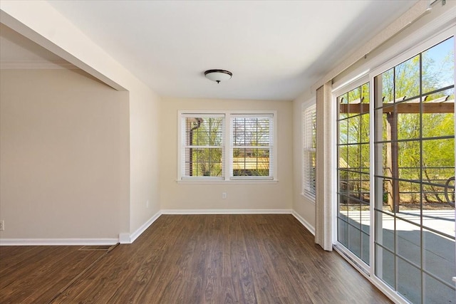 spare room featuring baseboards and dark wood-type flooring