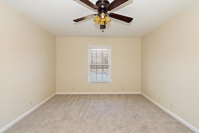 spare room featuring baseboards, light carpet, and ceiling fan