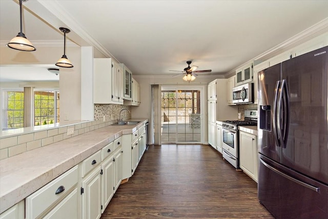 kitchen featuring ornamental molding, a sink, light countertops, glass insert cabinets, and appliances with stainless steel finishes