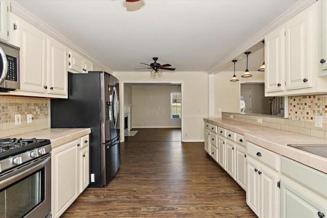 kitchen with dark wood-type flooring, appliances with stainless steel finishes, crown molding, light countertops, and ceiling fan