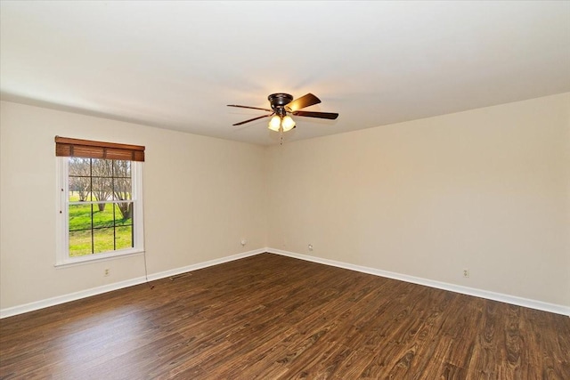 spare room featuring ceiling fan, dark wood-type flooring, and baseboards
