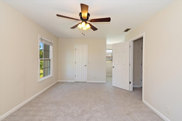 spare room with baseboards, a ceiling fan, visible vents, and light carpet