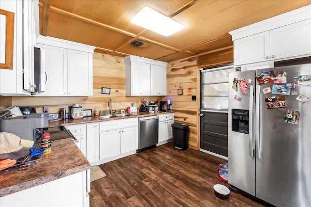 112 Shasteen St, Estill Springs, TN 37330 - kitchen with dark wood-style flooring, white cabinets, wooden walls, appliances with stainless steel finishes, and a sink