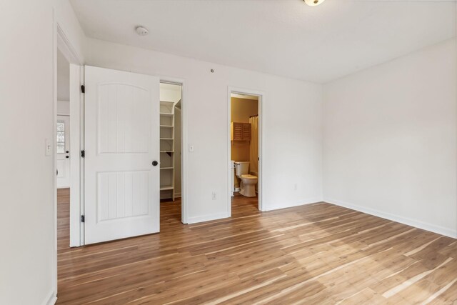 162 N Poole St, Ashland City, TN 37015 - unfurnished bedroom with light wood finished floors, a spacious closet, baseboards, a closet, and ensuite bath