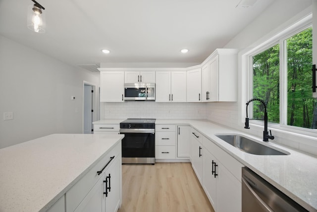 kitchen featuring decorative backsplash, a sink, light stone counters, white cabinets, and stainless steel appliances