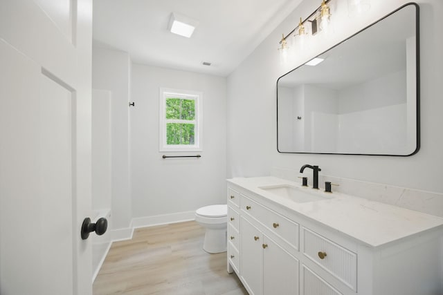 bathroom with baseboards, wood finished floors, toilet, and vanity