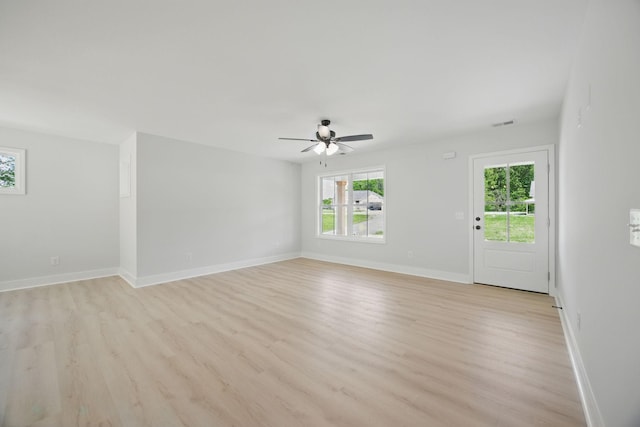 unfurnished living room with ceiling fan, baseboards, and light wood-type flooring