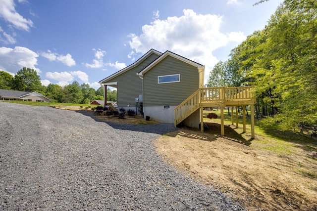 back of house with stairs, gravel driveway, and a deck