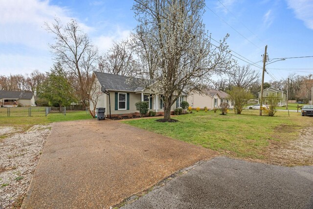 view of front facade with concrete driveway, a front lawn, and fence