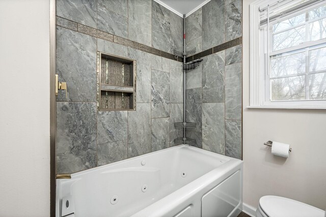 bathroom featuring baseboards, toilet, and a combined bath / shower with jetted tub