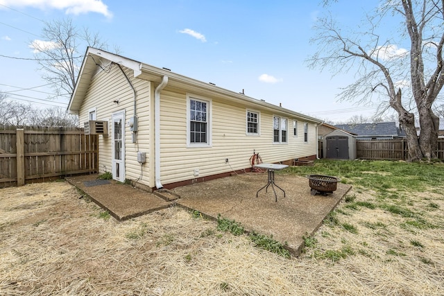 back of property featuring a shed, an outdoor fire pit, a fenced backyard, an outbuilding, and a patio