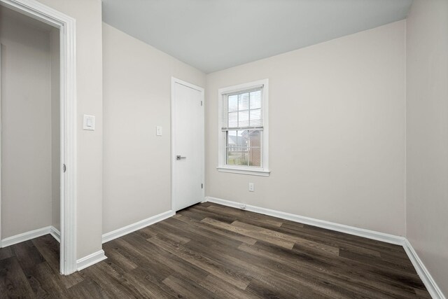 empty room with baseboards and dark wood-style flooring