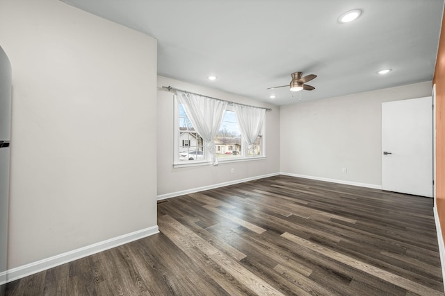 spare room featuring dark wood-type flooring, baseboards, ceiling fan, recessed lighting, and arched walkways