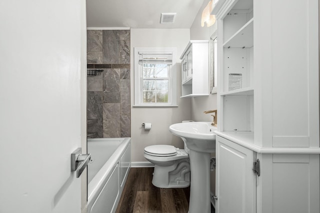 bathroom with washtub / shower combination, wood finished floors, visible vents, baseboards, and toilet