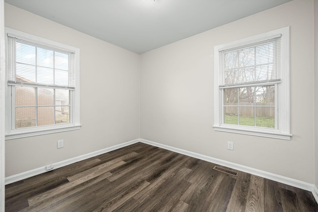 unfurnished room featuring dark wood-type flooring, baseboards, and visible vents