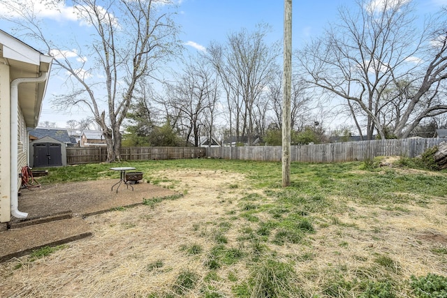 view of yard with an outbuilding, a fenced backyard, a shed, and a fire pit