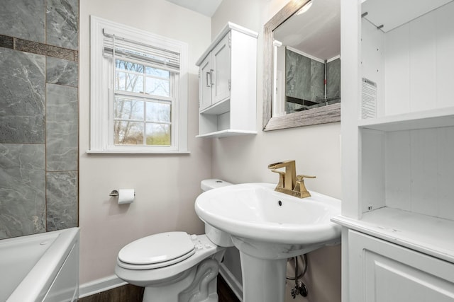 bathroom featuring toilet, a bathtub, and baseboards