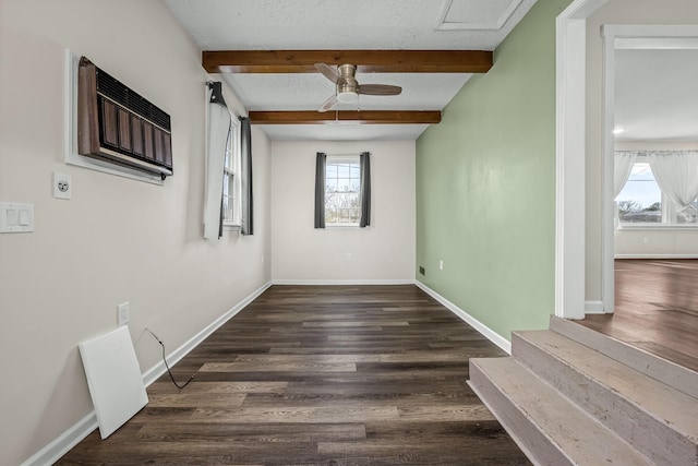 empty room featuring beamed ceiling, wood finished floors, baseboards, and a textured ceiling