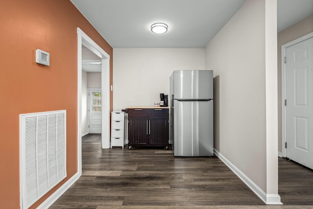 kitchen featuring visible vents, baseboards, dark brown cabinetry, freestanding refrigerator, and dark wood-style flooring