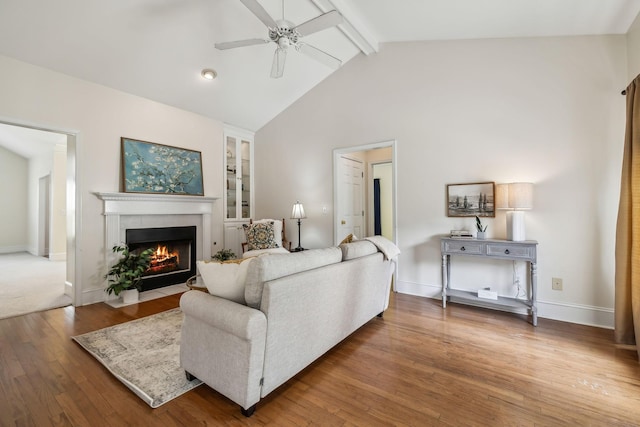 living room featuring hardwood / wood-style flooring, a ceiling fan, a fireplace, baseboards, and beamed ceiling