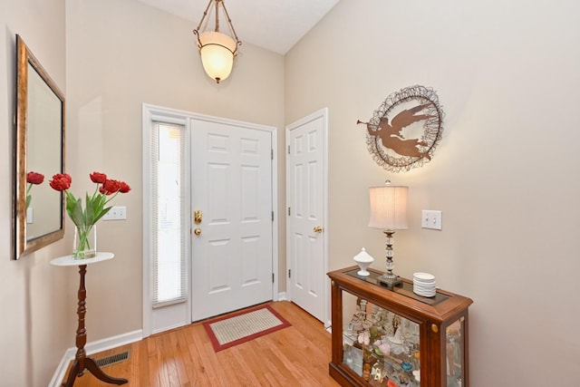 foyer with baseboards, visible vents, and light wood-style floors