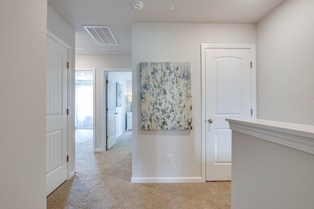 hall featuring light carpet, visible vents, and baseboards