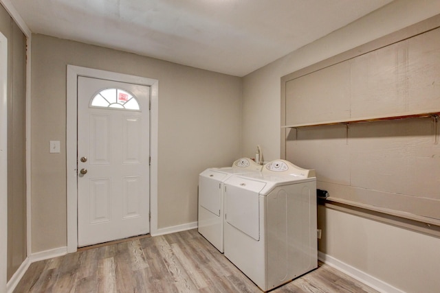 washroom with light wood-type flooring, baseboards, separate washer and dryer, and laundry area