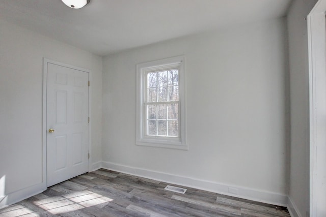 unfurnished room featuring visible vents, baseboards, and wood finished floors