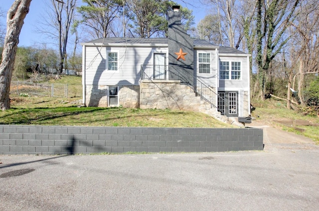 view of front of property with a chimney, a front yard, and fence