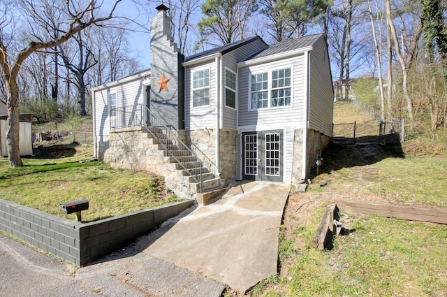 exterior space with fence, french doors, a lawn, and a chimney