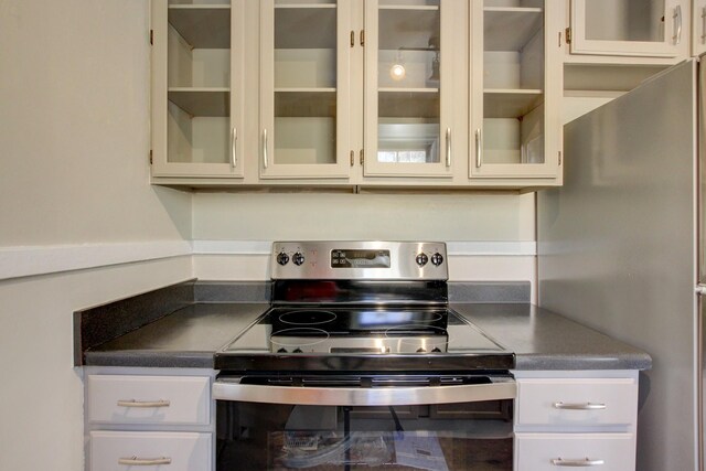kitchen with glass insert cabinets, dark countertops, and appliances with stainless steel finishes