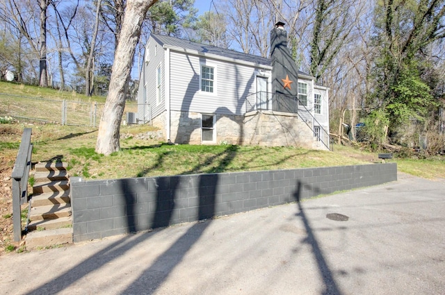 view of front of house featuring stairway, metal roof, a chimney, and fence