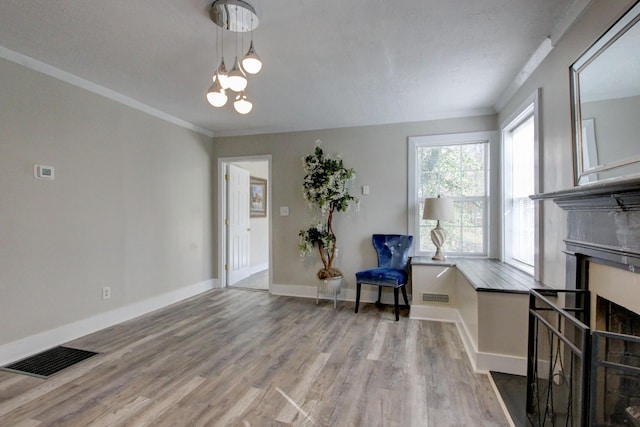living area featuring visible vents, baseboards, wood finished floors, and crown molding