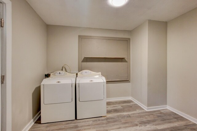 washroom featuring laundry area, light wood-style floors, independent washer and dryer, and baseboards