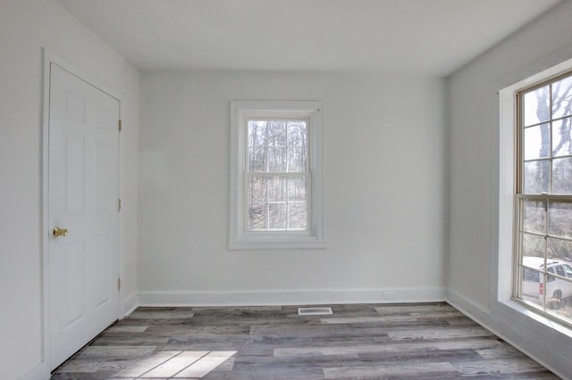 spare room with baseboards and wood finished floors