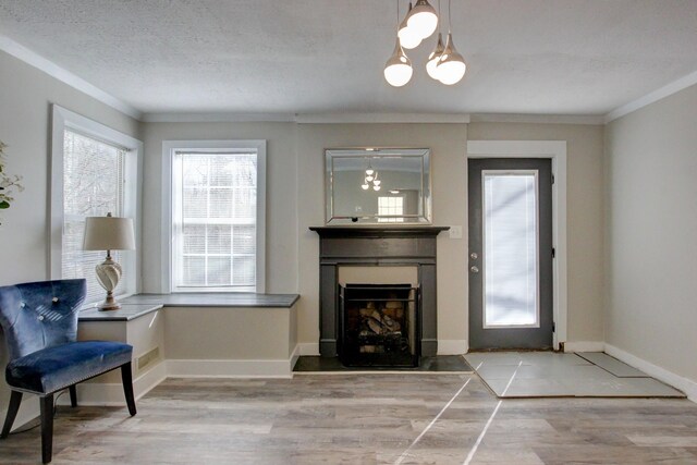 living room with ornamental molding, a textured ceiling, a fireplace, light wood finished floors, and baseboards