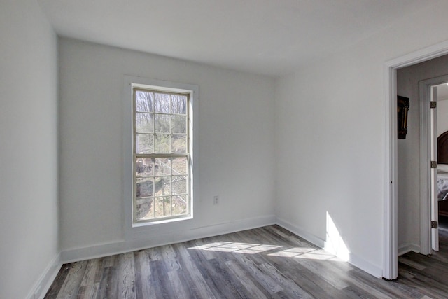 unfurnished room featuring a healthy amount of sunlight, baseboards, and wood finished floors