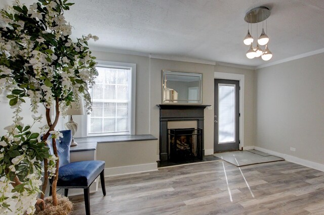 sitting room featuring baseboards, wood finished floors, a fireplace, and crown molding