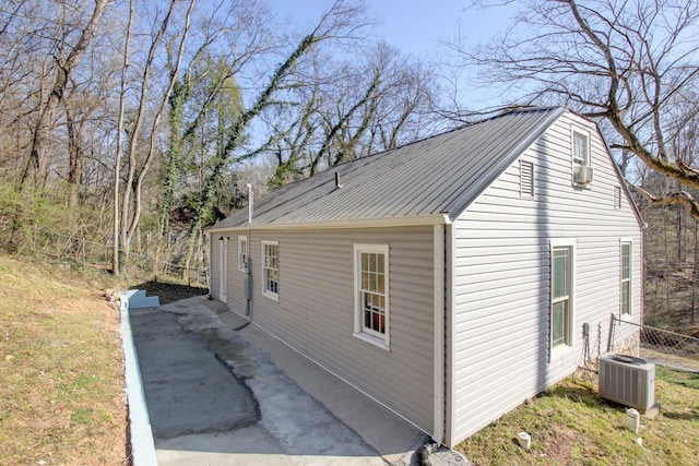 view of home's exterior featuring metal roof, central AC, and fence