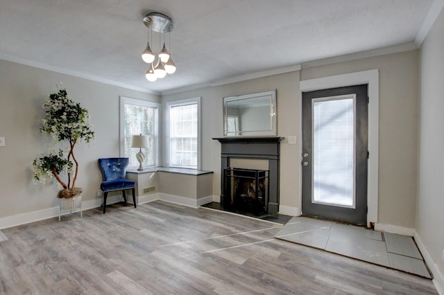 sitting room featuring a notable chandelier, ornamental molding, wood finished floors, a fireplace, and baseboards